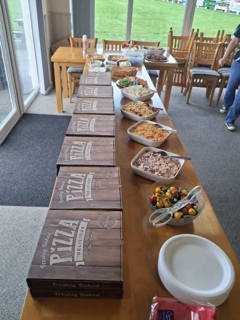 A long table set with a pizza buffet and homemade sides