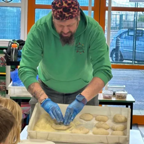 Simon rolling dough balls by hand into a floured tray