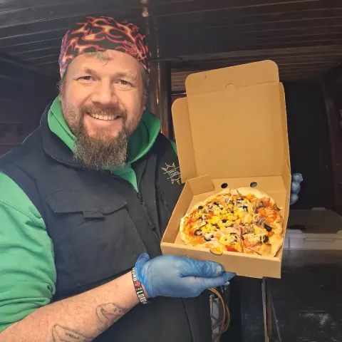 Simon holding up a boxed pizza