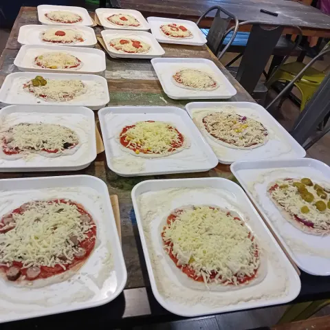 Pizzas made by children at a workshop, ready for the oven